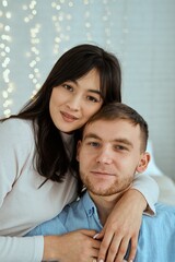 Fototapeta premium Happy girl hugging a guy in a blue shirt. Attractive couple posing together for a family photo.
