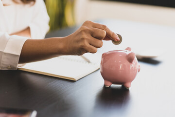 Obraz na płótnie Canvas Close-up woman putting coin in piggy bank. Money saving concept.