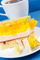 Creamy sweet sponge cake with different layers and jelly. Cup of coffee. Festive dessert