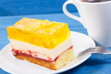 Creamy sweet sponge cake with different layers and jelly. Cup of coffee. Dessert for celebrations