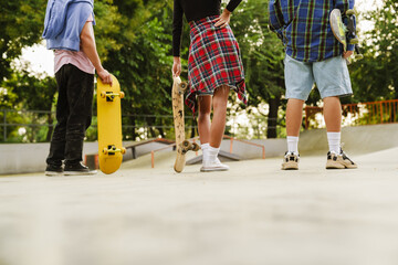 White teenagers holding skateboards while spending time at skate park