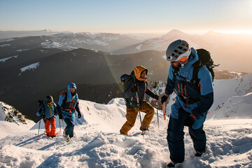 group of male tourists climbing up at snow-covered mountain trail against the backdrop of a...
