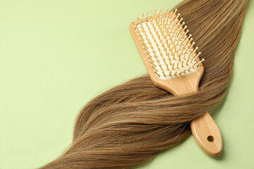 Female hair with hairbrush on green background