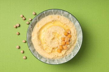 Plate of hummus on green background, top view