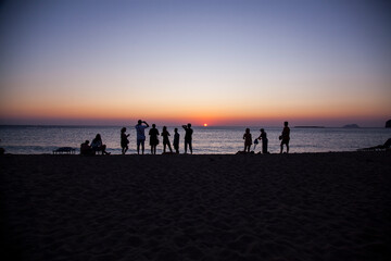 People in silhuette watching a sunset in front of the sea