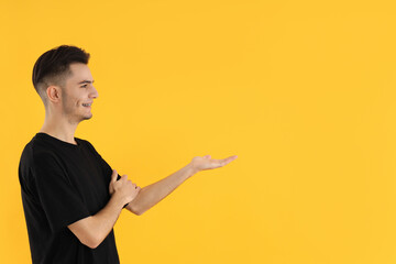 Attractive young man in t-shirt on yellow background