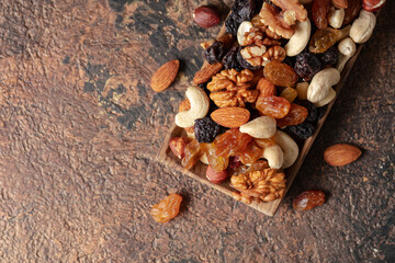 Mix of nuts and raisins on a brown rustic background.