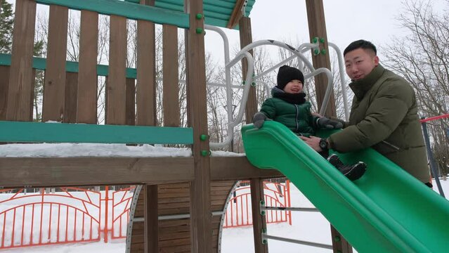 Father helping little son to slide down the hill
