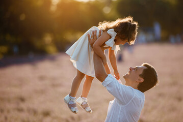 Father is playing with his daughter kid outdoors.