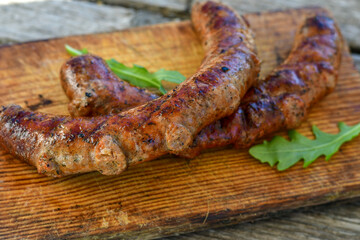 Grilled  pork  juicy sausages on wooden board outdoors. Grilling food, bbq, barbecue, picnic