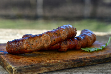 Grilled  pork  juicy sausages on wooden board outdoors. Grilling food, bbq, barbecue, picnic