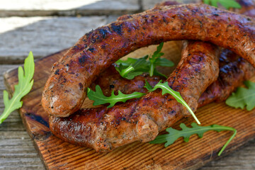 Grilled  pork  juicy sausages on wooden board outdoors. Grilling food, bbq, barbecue, picnic
