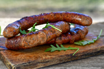 Grilled  pork  juicy sausages on wooden board outdoors. Grilling food, bbq, barbecue, picnic