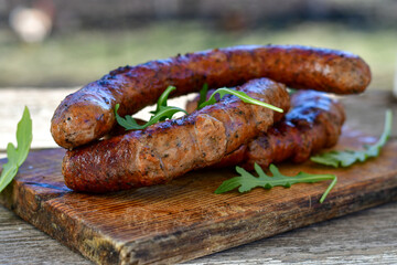 Grilled  pork  juicy sausages on wooden board outdoors. Grilling food, bbq, barbecue, picnic