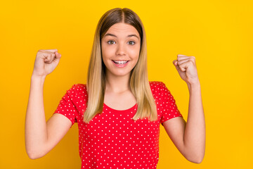 Photo of delighted positive girl raise fists celebrate luck toothy smile isolated on yellow color background