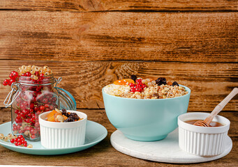 Healthy breakfast of granola bowl with berries and honey on wooden background. Copy space
