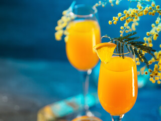 mimosa drink and flowers on a blue background. Cocktail for March 8