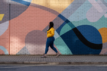 UK, South Yorkshire, Woman with braided hair walking by colorful wall