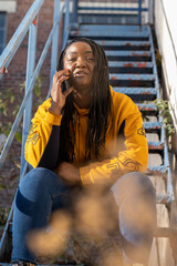UK, South Yorkshire, Woman with braided hair talking on phone on steps