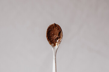 Spoon with chocolate on a light background