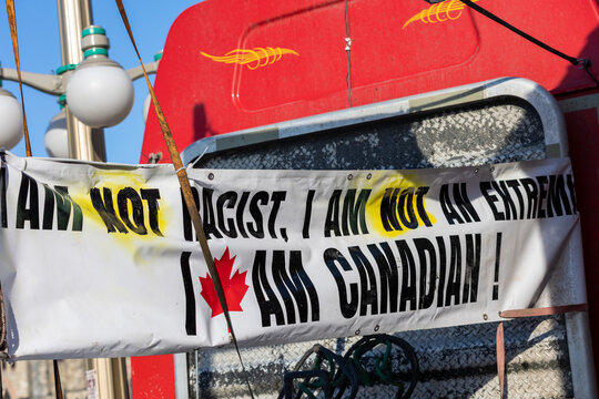 Banner attached to back of red truck reading " I am not racist, I am not an extremist, I am Canadian" 