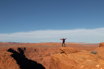 Young man opening arms at horseshoe bend in the grand canyon