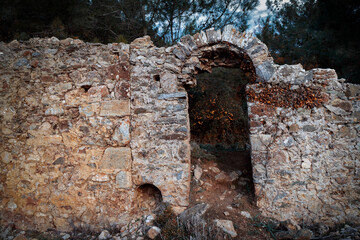 Ancient city of Syedra, Turkey. Antique ruins of historic building with arch and green trees on background. Selective focus.