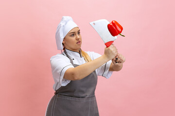 Comic portrait of lady-cook, chef in white hat and kitchen apron isolated on pink background....