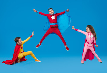 Kids in superhero costumes showing superpowers in studio