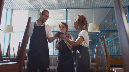 Coffee shop workers chatting and drinking coffee relaxing after closing. Realtime