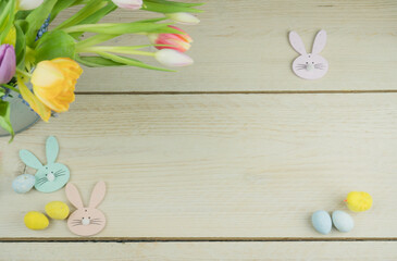 Wielkanoc, tło na życzenia z tulipanami, króliczkami i jajkami, aranżacja na drewnianym stole.