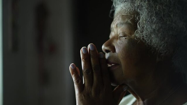 An older African woman praying to God closing eyes with HOPE and FAITH