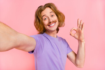Self-portrait of attractive cheerful guy showing ok-sign ad advert agree isolated over pink pastel...