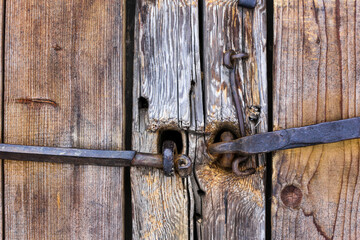 Log old house. Doors, gates. Forged rusty metal door handles, bolts, hinges, hooks. Shabby tree, aged wood structure.