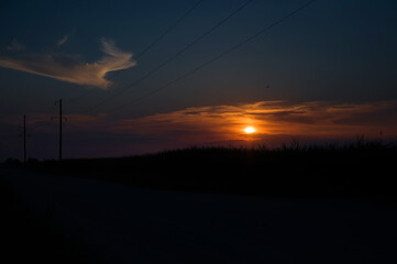 beautiful sunset in the steppe, the sun goes beyond the horizon, highlighting the clouds, painting the sky in special color shades. Natural landscape. reflection, blue sky and red sunlight.