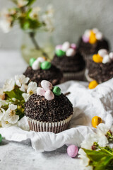Homemade Easter chocolate cupcakes with chocolate butter cream frosting and candy eggs. Easter brunch. spring blossom decoration. on white linen tableclouth Happy easter day. Easter recipes.