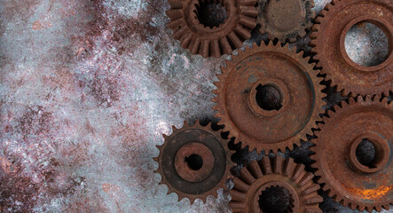 Parts of an old mechanism made of metal gears and other parts covered with rust on a rusty textural background. Technical concept with a copy space, horizontal orientation, top view