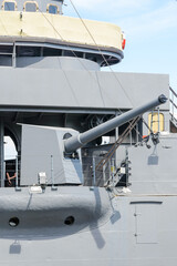 Big gun cannon on right side of warship. Safety boat on a ship