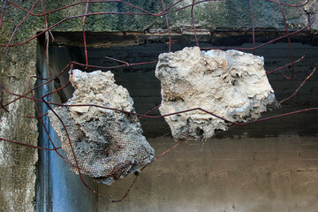 Slabs of concrete debris hanging on metal rebars in a demolished building