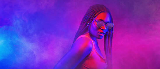 Portrait of fashion young girl in cool sunglasses in red and blue neon light in the studio