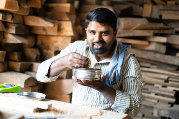 Carpenter eating food from lunch box at shop - concept of taking break, small business and artisan