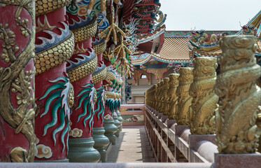 Fototapeta premium Chonburi, Thailand - 05 Feb 2022 : Panoramic of Sculptured dragons pillars and corridor in Chinese-style temple. Wihan Thep Sathit Phra Ki Ti Chaloem, Selective focus.