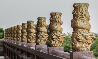 Chonburi, Thailand - 05 Feb 2022 : Column pillar at oriental golden hand rail on corridor in Chinese-style temple. Emboss gold pillars stucco, Selective focus.