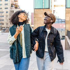 two young African American women walking in urban scenery, female best friends chatting and...