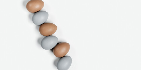 Painted Easter eggs gray, beige colored in row on white background with copy space. Chicken egg natural pastel shades. Easter holiday food, minimal design aesthetic flat lay