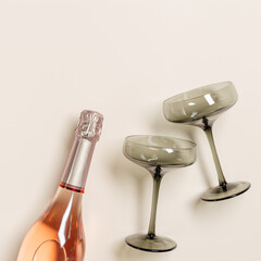Rose champagne bottle and champagne glasses from tinted grey glass on beige table background. Minimal drink concept. Trendy wine glasses, vintage colored glass. Creative top view.