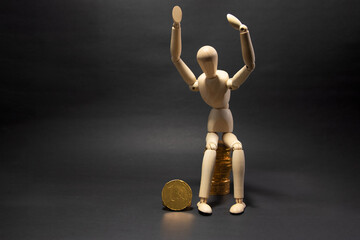 Wooden figure mannequin sitting on a pile of coins being happy on a black background. Business Concept