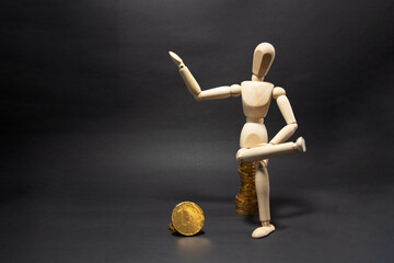 Wooden figure mannequin sitting on a pile of coins being happy on a black background. Business Concept