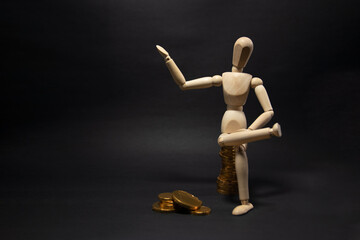 Wooden figure mannequin sitting on a pile of coins being happy on a black background. Business Concept