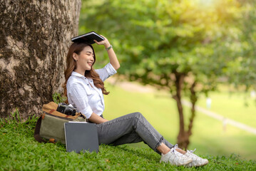 Smiling cute Asian female student holding a book on her head.